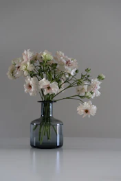 A minimalist luxury floral arrangement in a sleek white showroom setting.