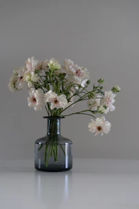 A minimalist luxury floral arrangement in a sleek white showroom setting.
