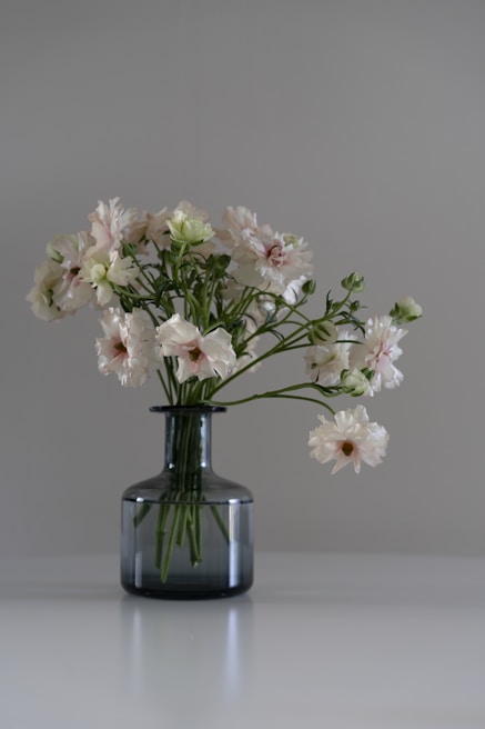 An elegant home décor box featuring lush greenery and soft pastel blooms arranged in a minimalist ceramic vase.