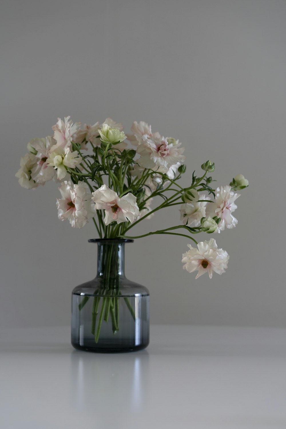 white and pink flowers in blue glass vase