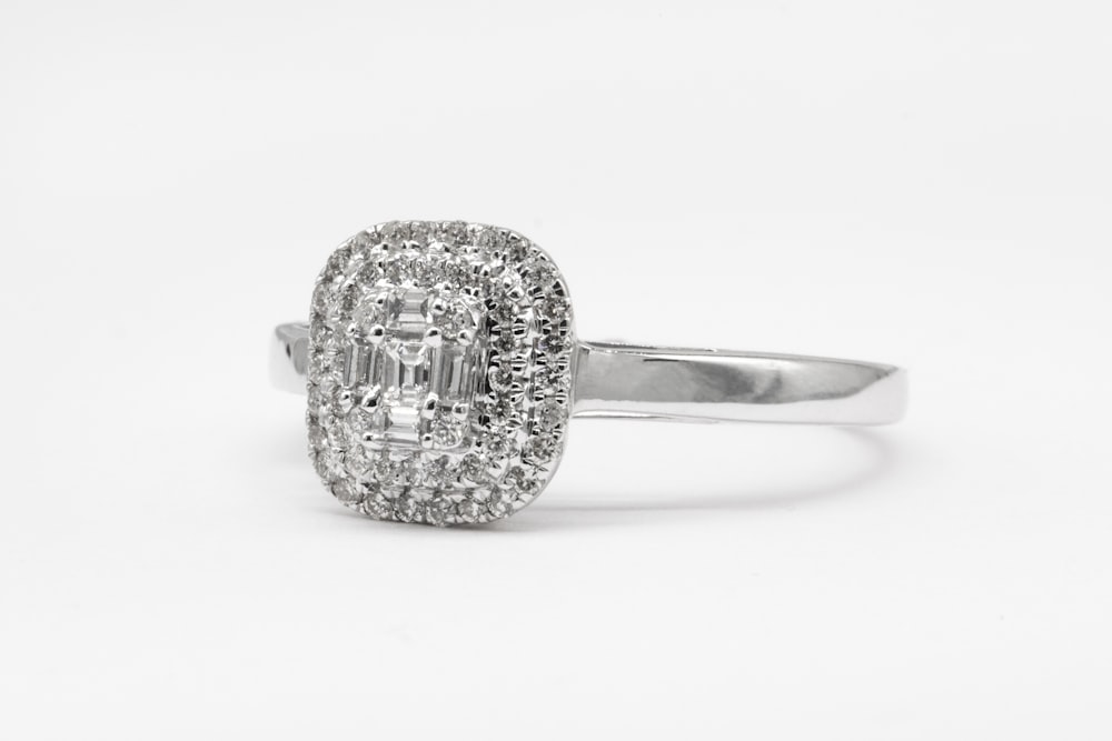 silver diamond studded ring on white surface