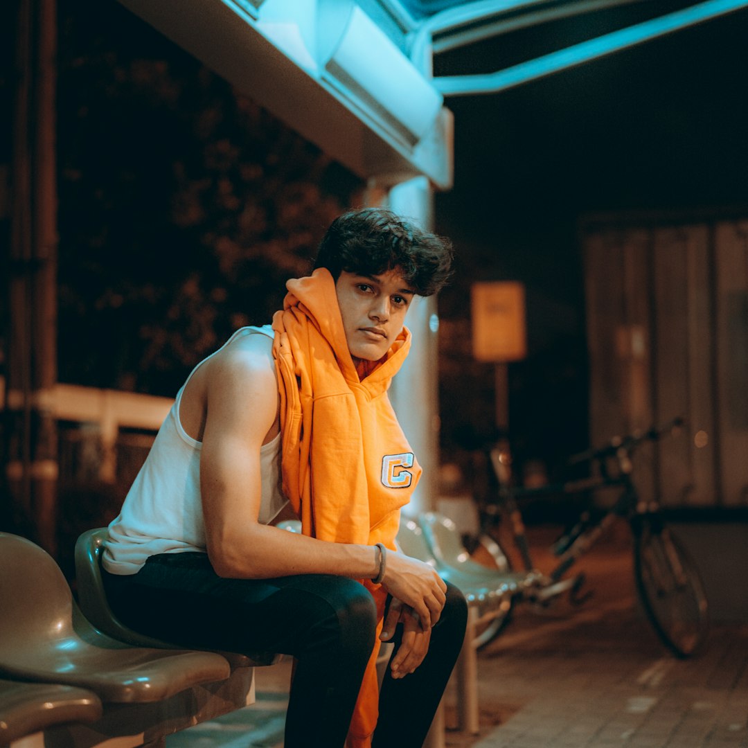 man in orange tank top sitting on black chair