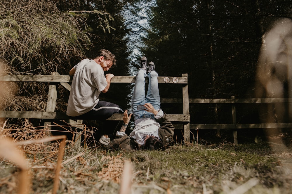 man and woman sitting on brown wooden bench during daytime