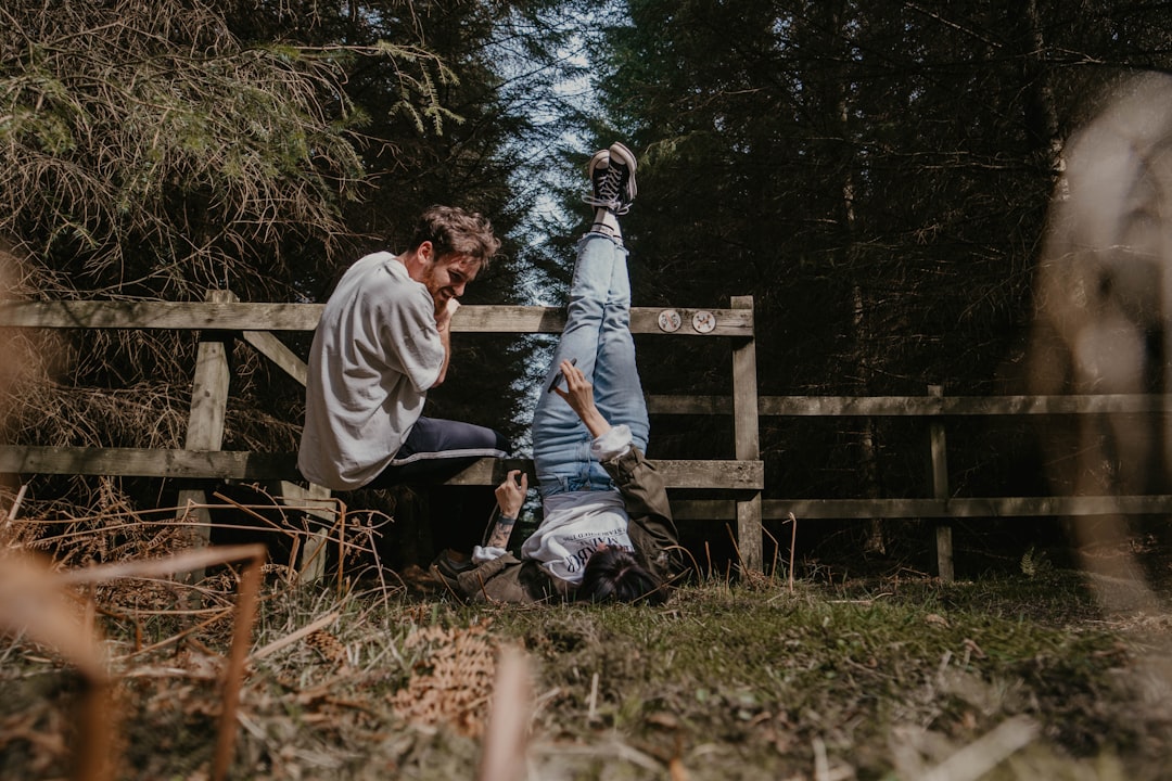 man in white crew neck t-shirt sitting on brown wooden bench