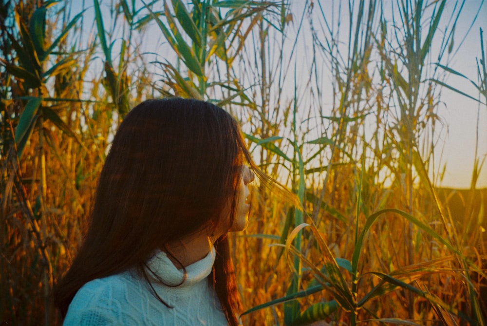 woman in white shirt standing near green grass during daytime