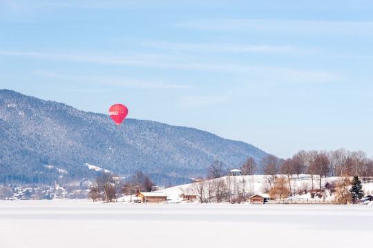 red hot air balloon flying over snow covered field during daytime in Rottach-Egern Germany