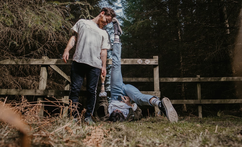 man and woman sitting on brown wooden fence during daytime