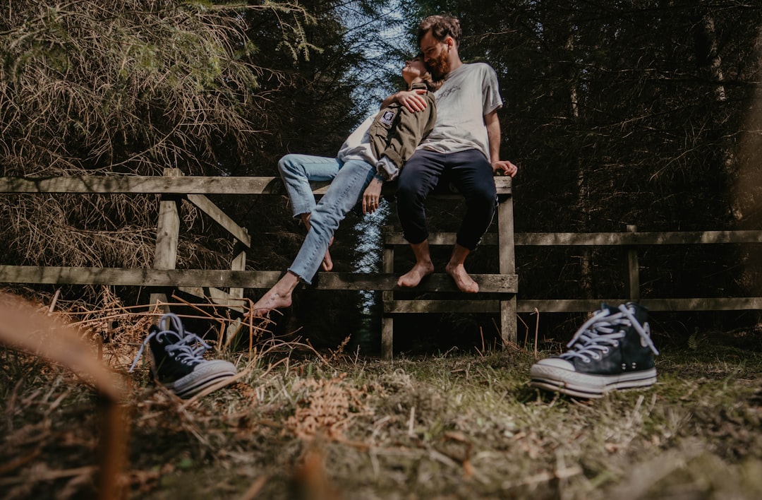 man and woman sitting on wooden fence