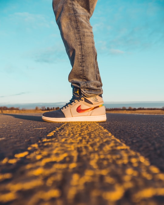 person in blue denim jeans and black and white nike sneakers standing on brown sand during in London Canada