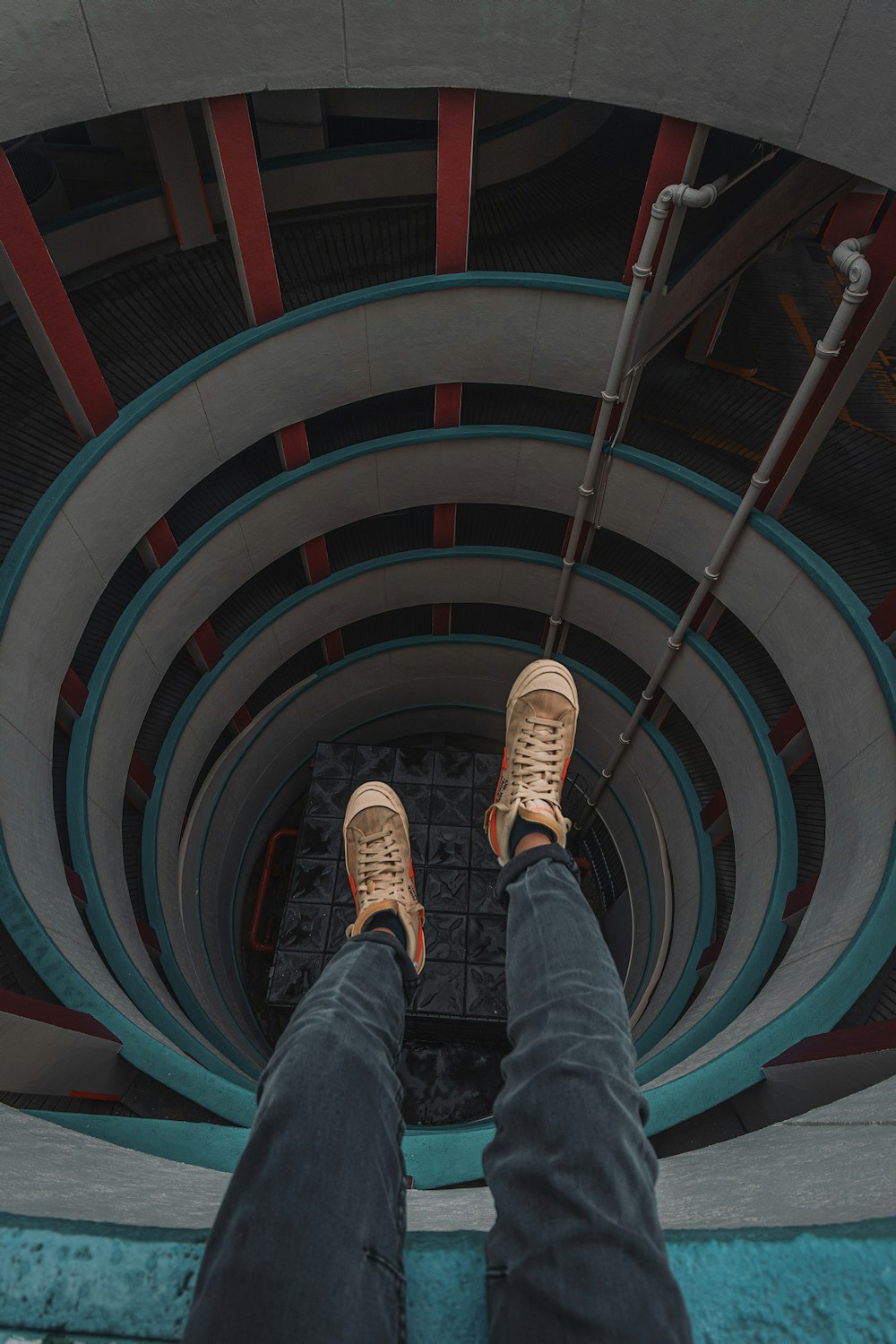 Person in blauen Jeans und braunen Sneakers auf einer Wendeltreppe