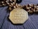 An intricately designed octagonal gold pendant featuring Sanskrit inscriptions is placed on a string of beads. The beads are a mix of round brown wooden beads and golden beads with detailed crafting.