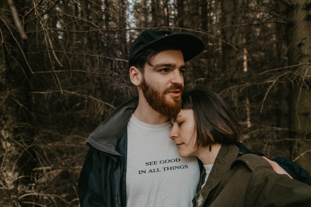 man in black jacket and black hat standing beside woman in gray crew neck shirt