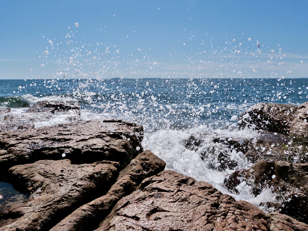 person standing on brown rock formation near body of water during daytime