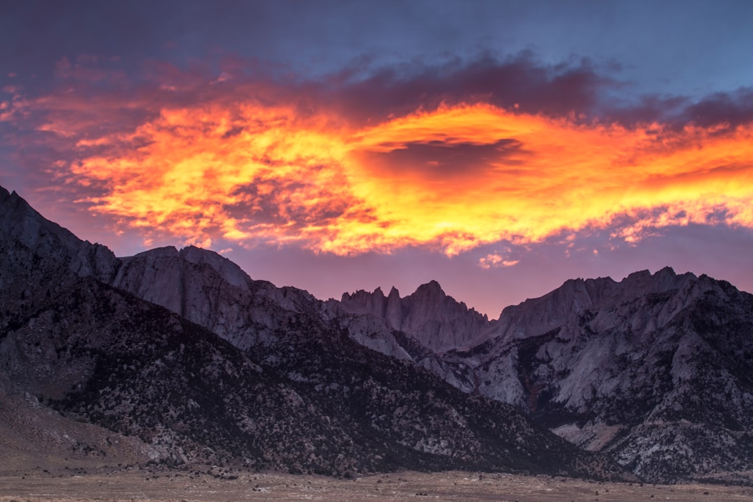 gray rocky mountain under orange and gray cloudy sky during sunset