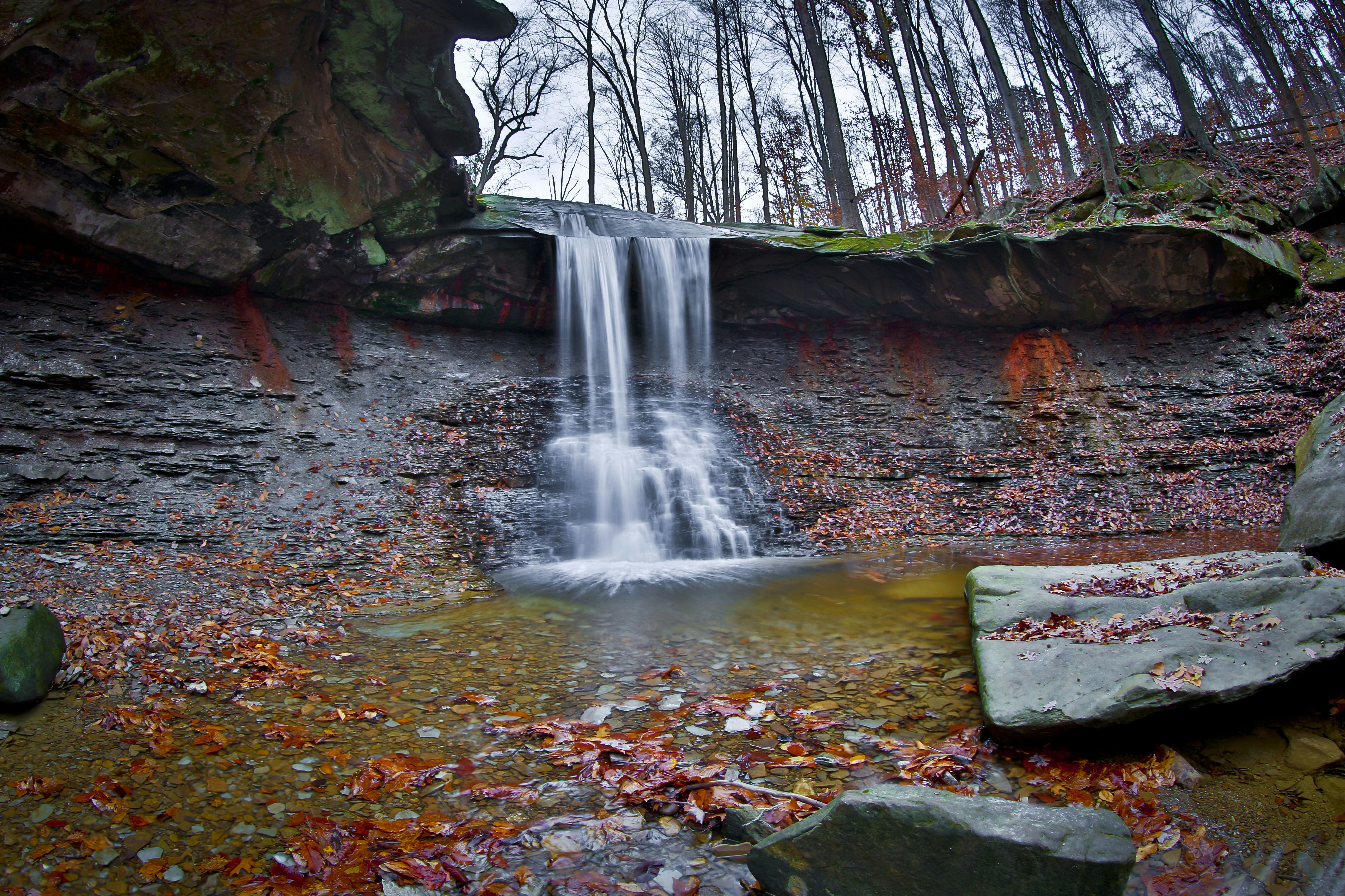water falls in the middle of brown and black rock formation