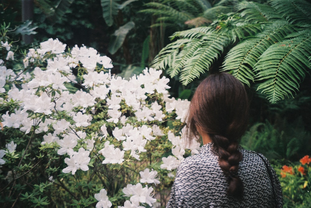 woman in black and white long sleeve shirt standing near white flowers