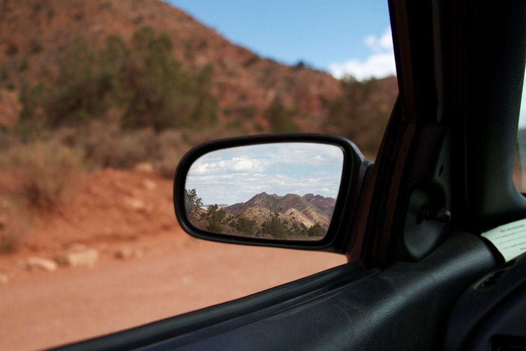 car side mirror showing brown mountain during daytime