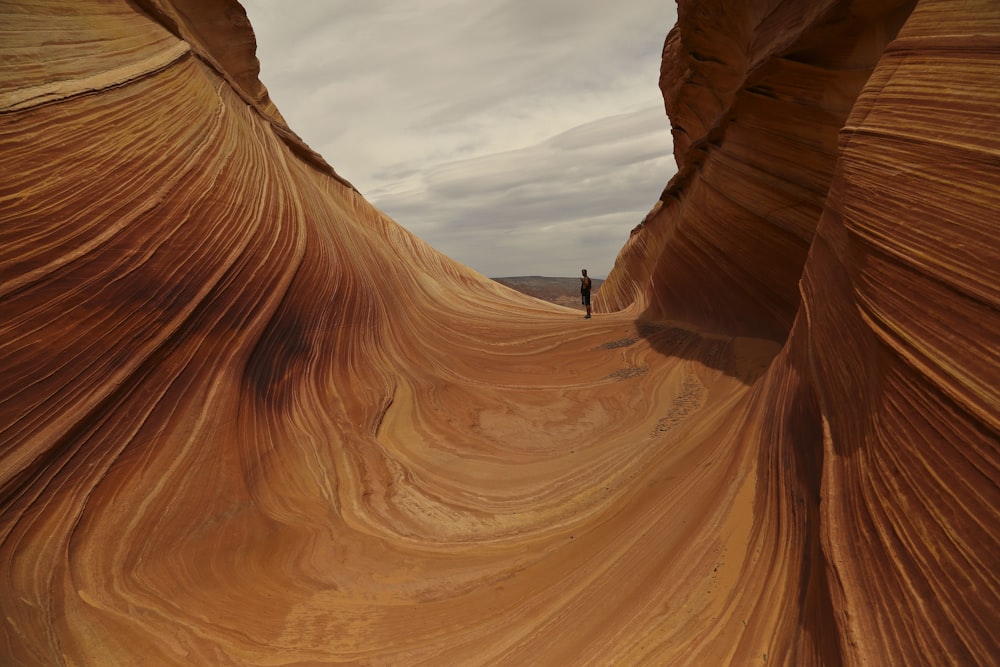 person in black jacket standing on brown rock formation during daytime