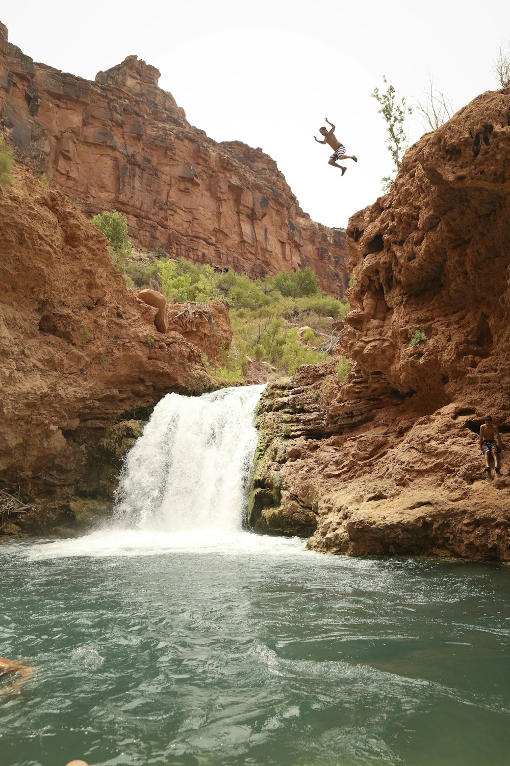 people standing on brown rock formation near waterfalls during daytime