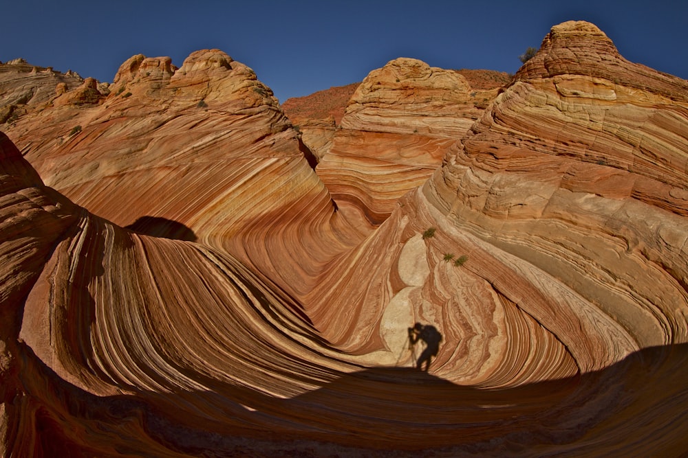 person walking on brown rock formation during daytime
