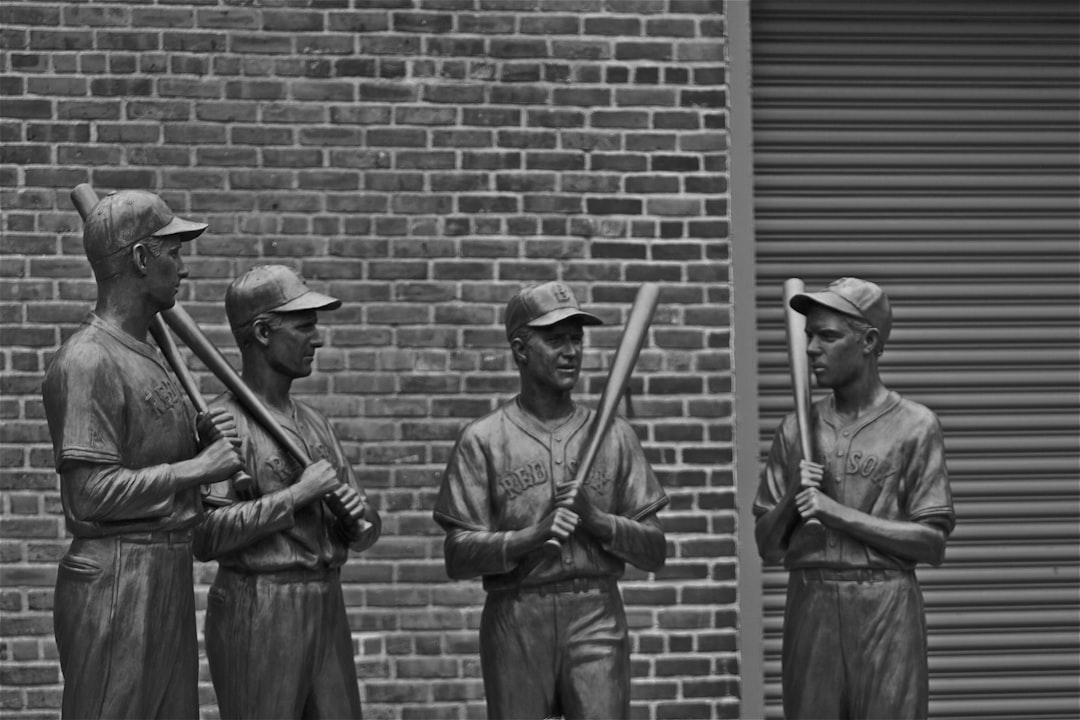 grayscale photo of 2 men standing near brick wall