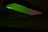 A mobile phone partially illuminated with green and red lighting, creating a contrast against the dark background. The illumination highlights the phone's texture and the outline of the camera.