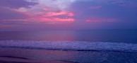 A tranquil beach scene with gentle waves lapping at the shore during sunset.