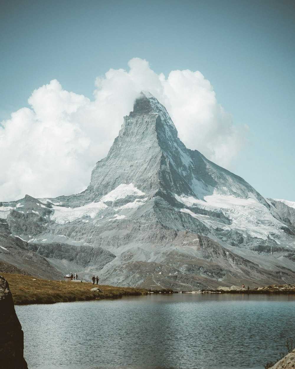 snow covered mountain near body of water during daytime