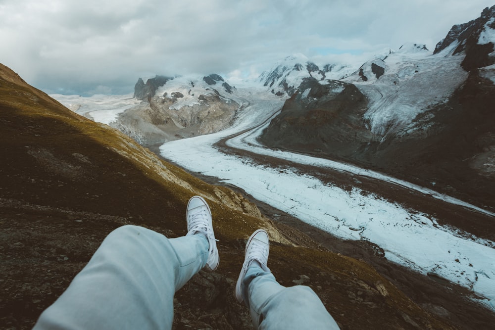 person in white pants and white shoes sitting on snow covered ground