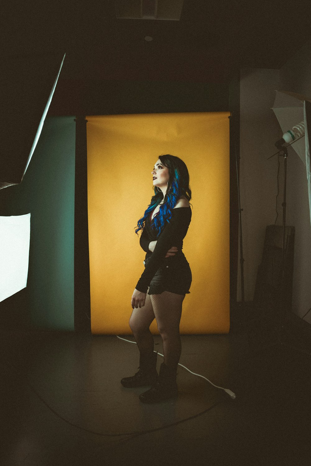 woman in black long sleeve shirt and black skirt standing beside white wall