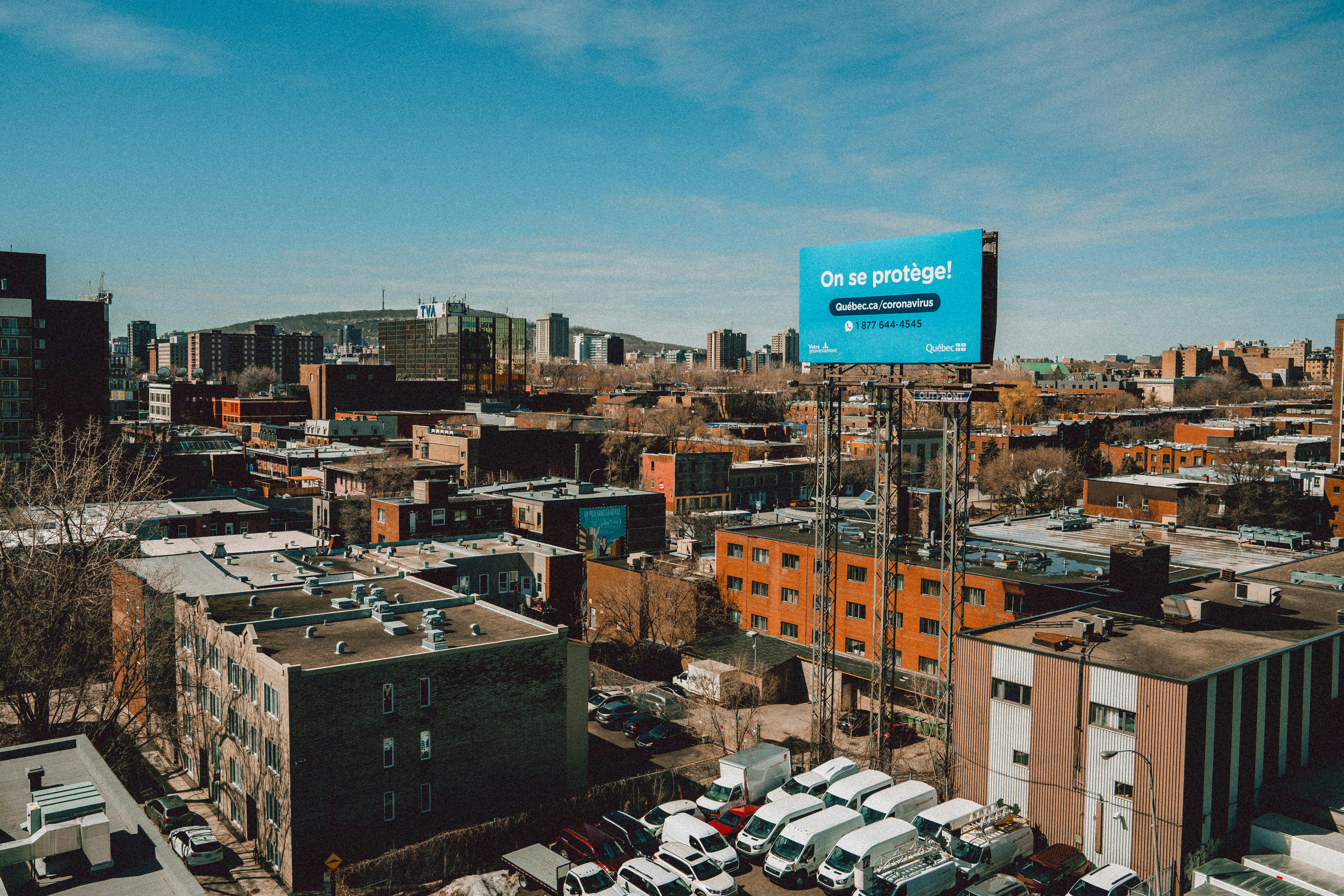 Large outdoor hoarding billboard on a busy city road, bright daytime, commercial district, clear blue sky