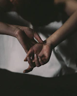 Close-up of hands gently holding, framed by soft natural light and shadows.