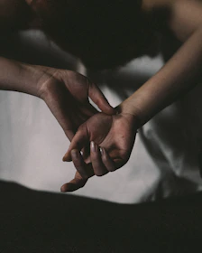 Warm, softly lit image of two hands gently holding each other in a comforting gesture.