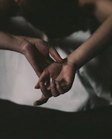 Warm, softly lit image of two hands gently holding each other in a comforting gesture.