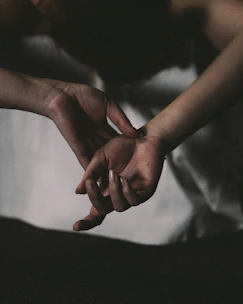 Close-up of hands gently intertwined, bathed in soft natural light.