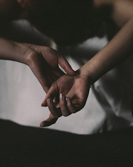 A warm, comforting scene of two hands gently holding each other under a soft glowing light.