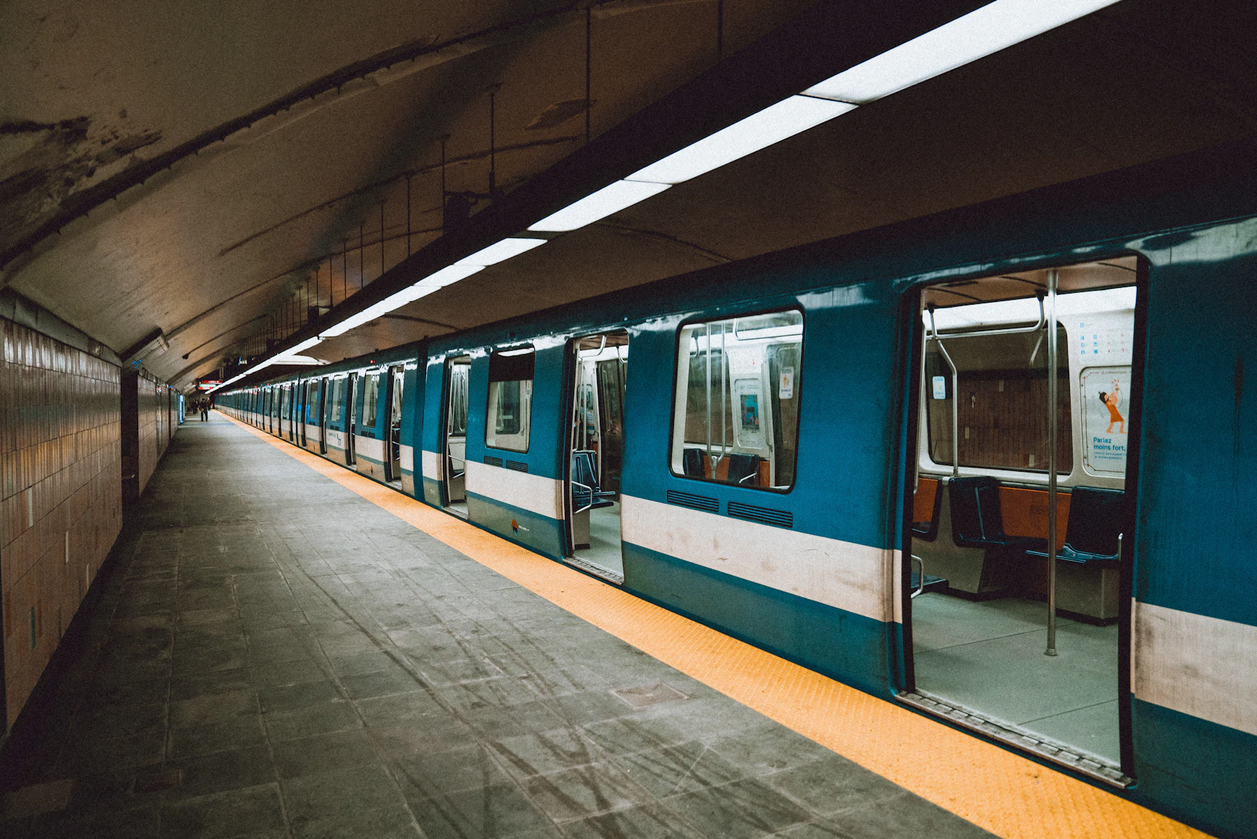 A blue-and-white train waits at a station platform.