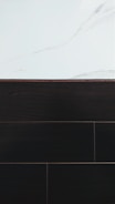A visually contrasting surface showing white marble with subtle gray veining at the top and dark wood or tile texture below, separated by a thin border.