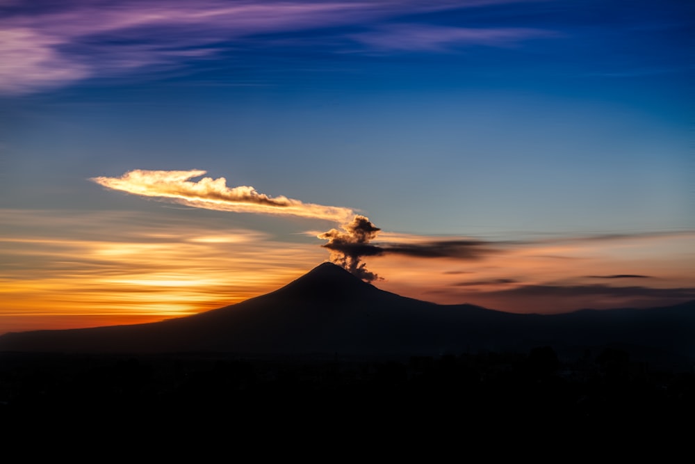 昼間の青空と白い雲の下に山のシルエット