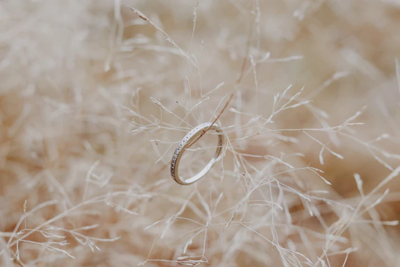 A delicate sterling silver ring resting on a soft pastel green fabric background.
