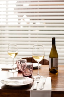 clear wine glass beside wine bottle on table