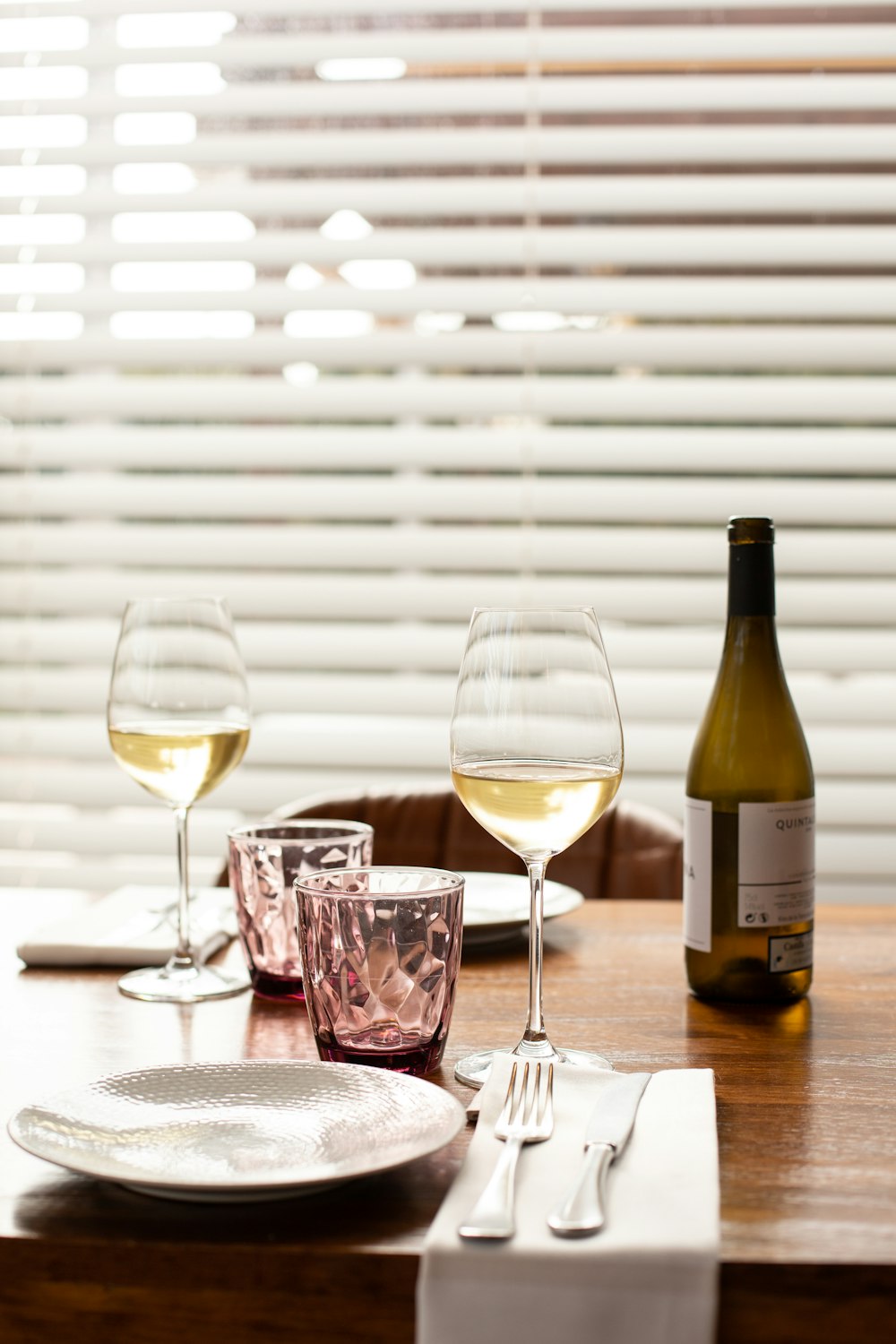 clear wine glass beside wine bottle on table