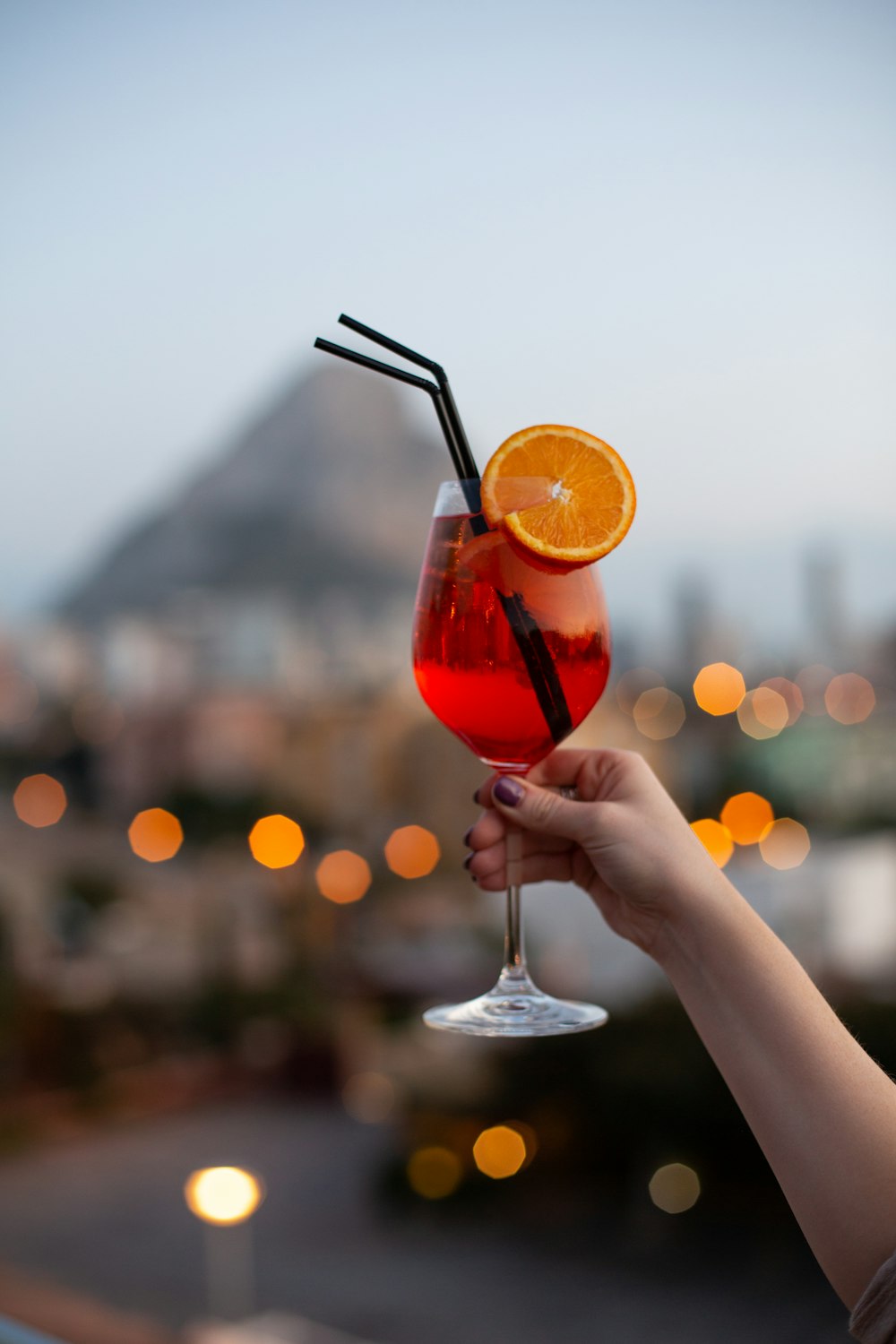 person holding clear wine glass with red liquid