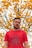 man in red crew neck shirt standing near yellow flowers