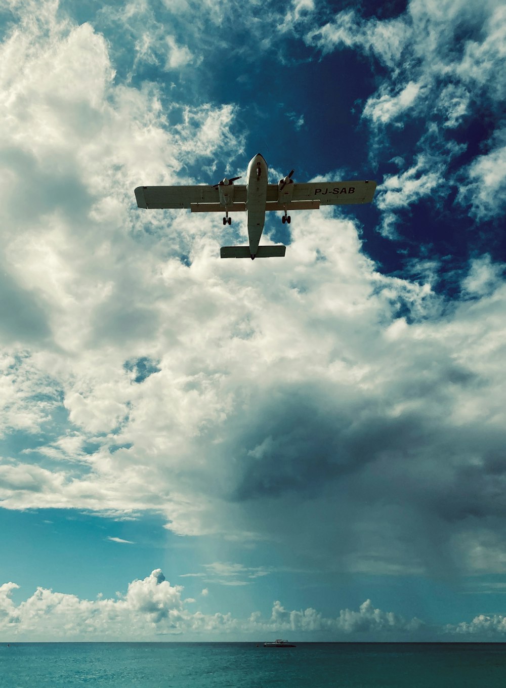 white airplane under white clouds and blue sky during daytime