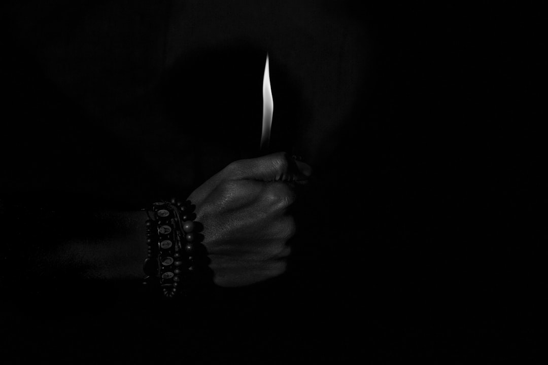 person holding lighted candle in dark room