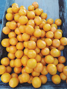 Fresh oranges and grapes displayed in a rustic wooden crate under natural sunlight.