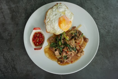 A vibrant plate of nasi goreng topped with fresh vegetables and a fried egg.