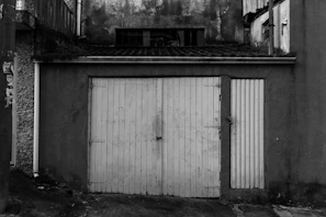 Before and after shot showing a worn garage door replaced with a fresh, clean one