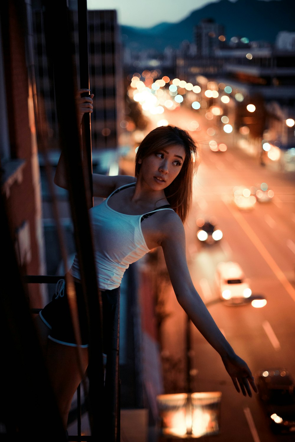 woman in white tank top standing beside brown wooden post during night time